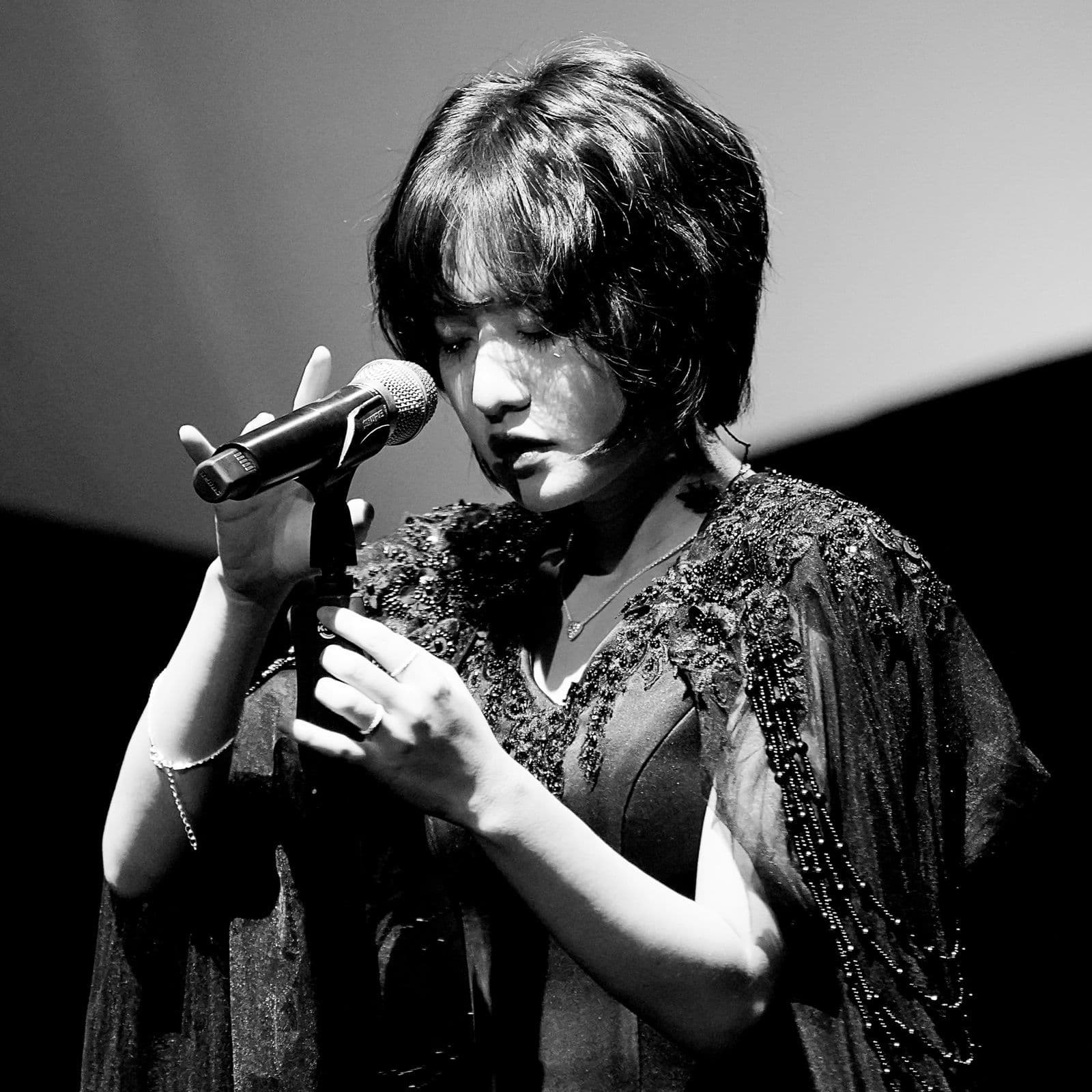 ライブステージ写真。マイクの前で息を呑む シム･ギュソン。単独コンサート「私たちの前の世界 」より。